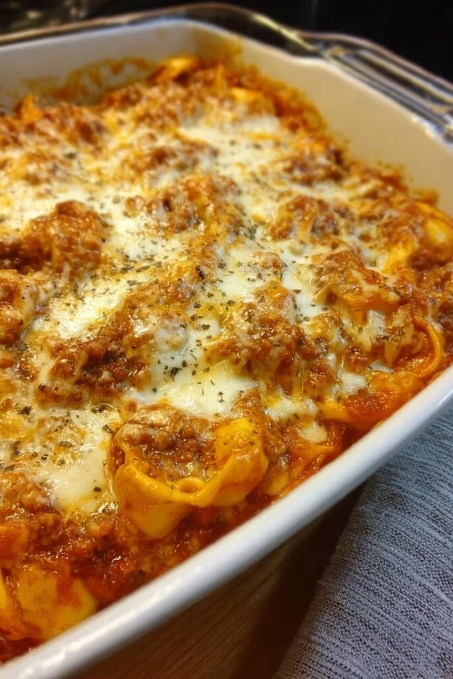 Cheesy baked tortellini casserole with meat sauce topped with cheese