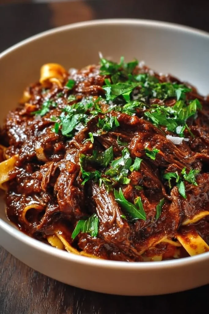 Delicious short rib ragu served over pasta with herbs and spices.