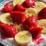 Delicious strawberry banana pudding topped with fresh fruit and whipped cream.